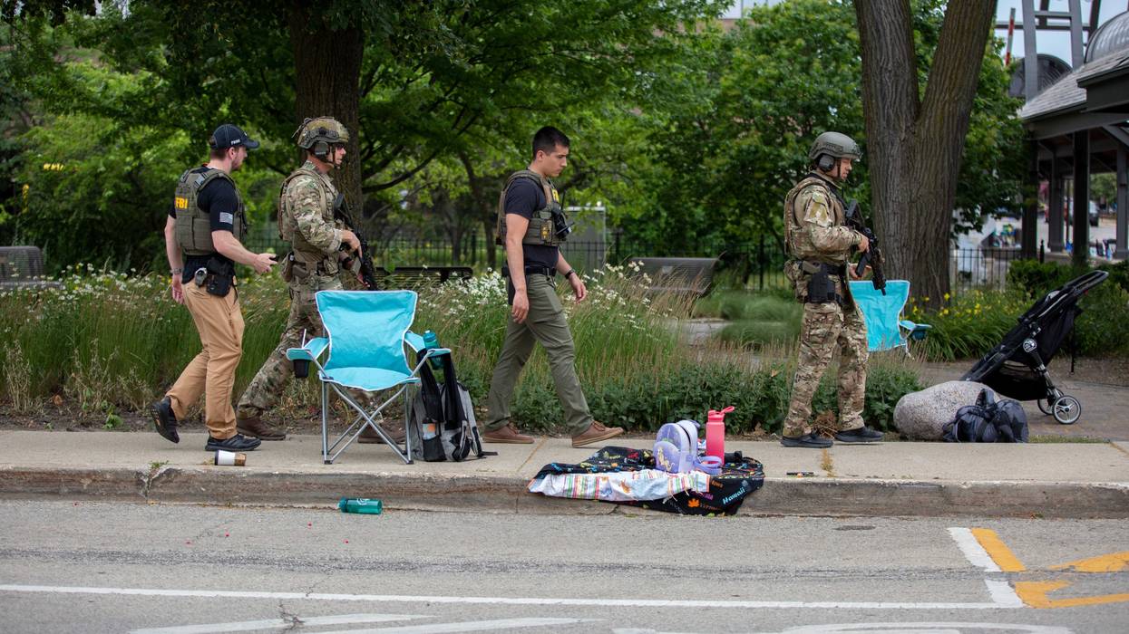 Authorities walk the scene of a Highland Park mass shooting