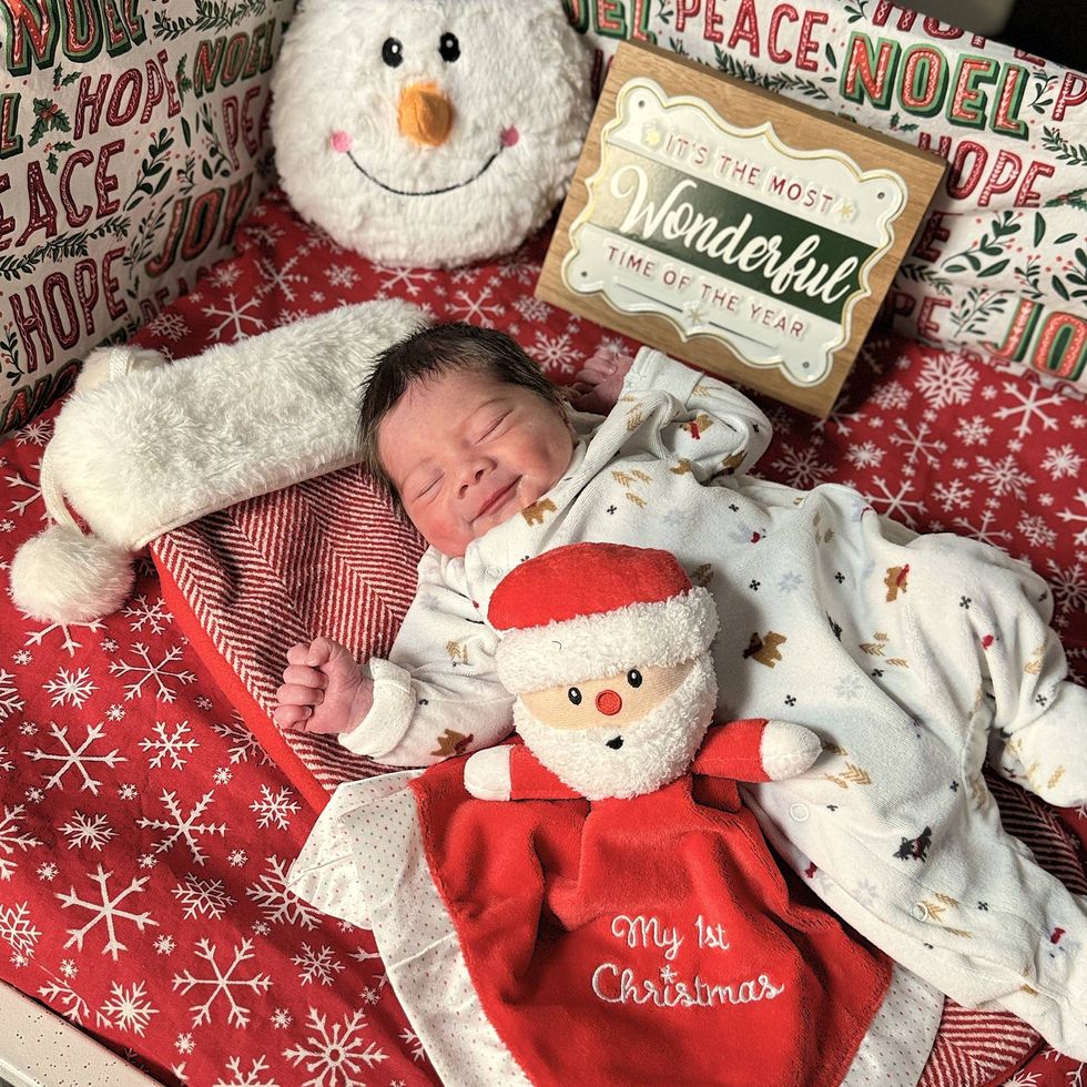 Baby in winter onesie with My 1st Christmas Santa doll