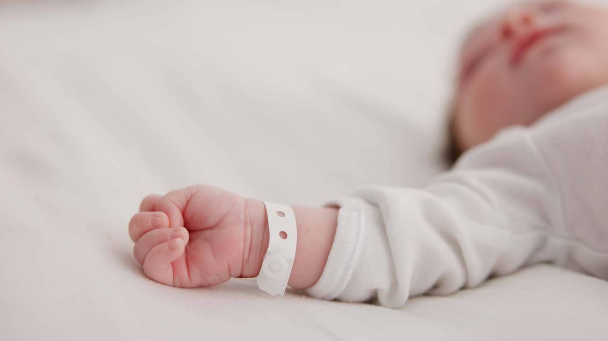 Baby, new born and hand with bracelet on bed for care