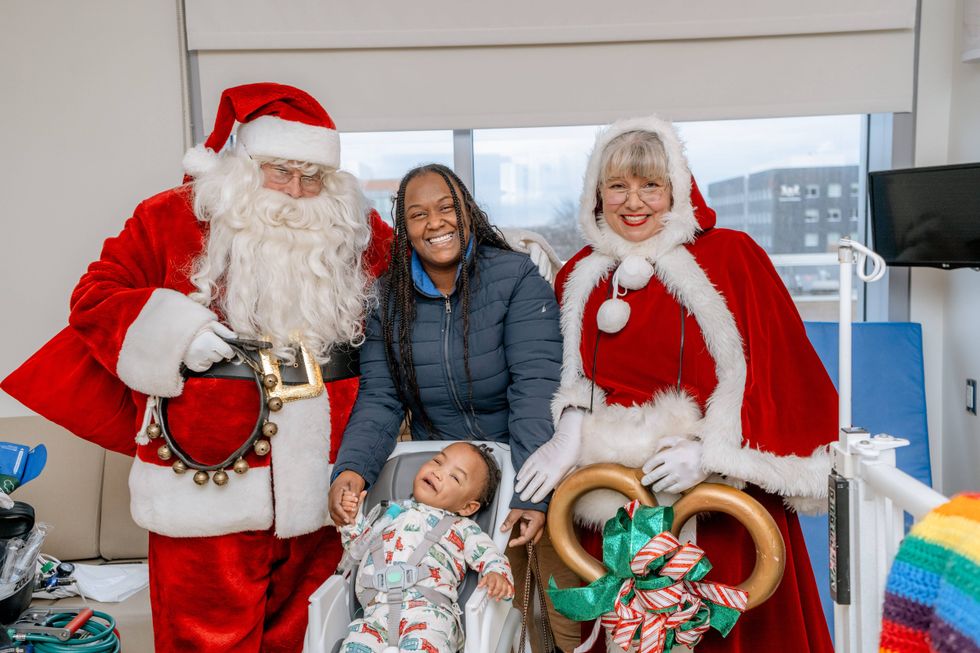 Baby with Santa and Mrs. Claus and smiling woman