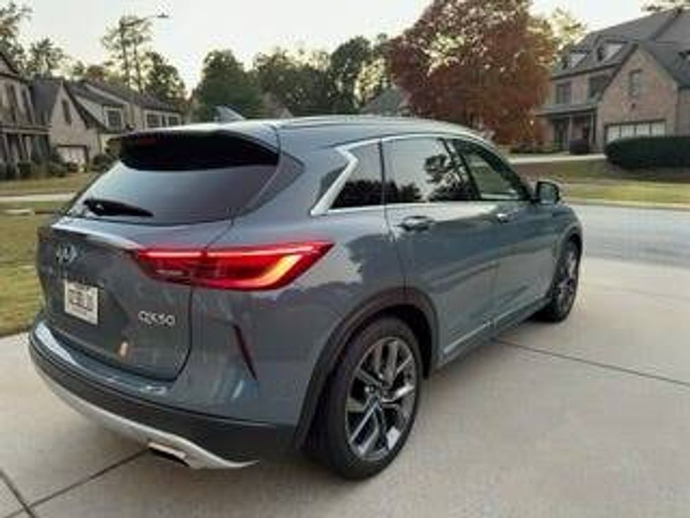Back angle of a gray 2024 Infiniti SUV, emphasizing its elegant lines and sophisticated appearance.