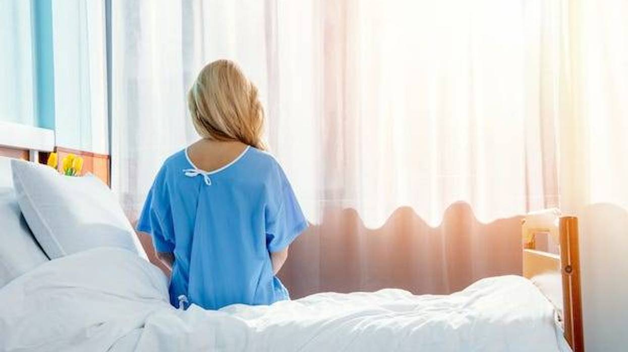 Back of woman sitting on bed in hospital room