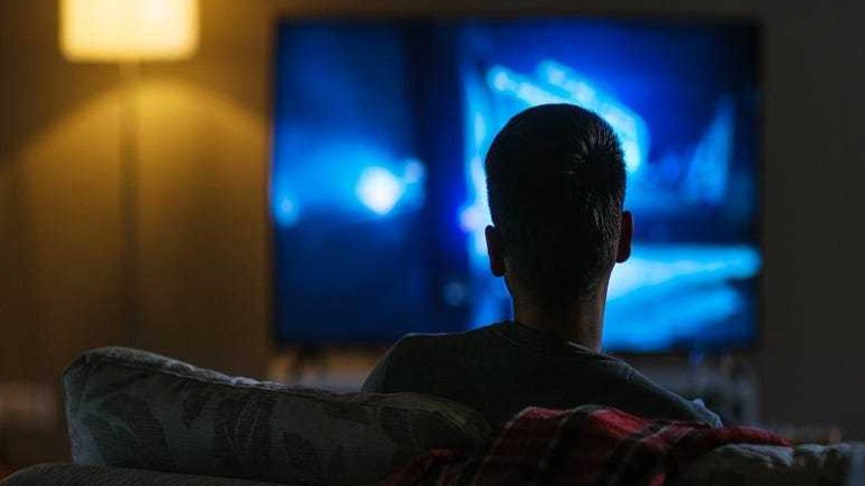 Back View of a Man Sitting on a Couch Watching Movie on His Big Flat Screen TV