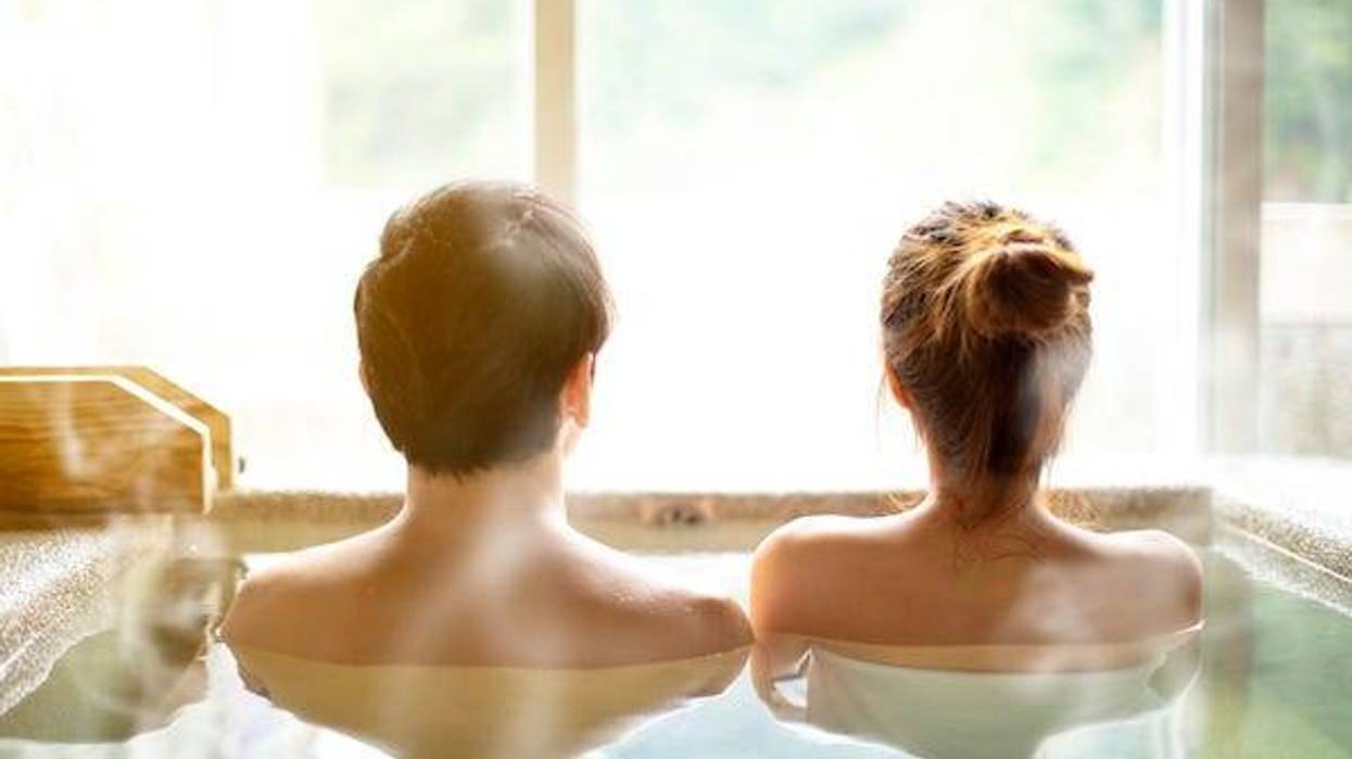 Back view of a young couple relaxing in a hot springs pool