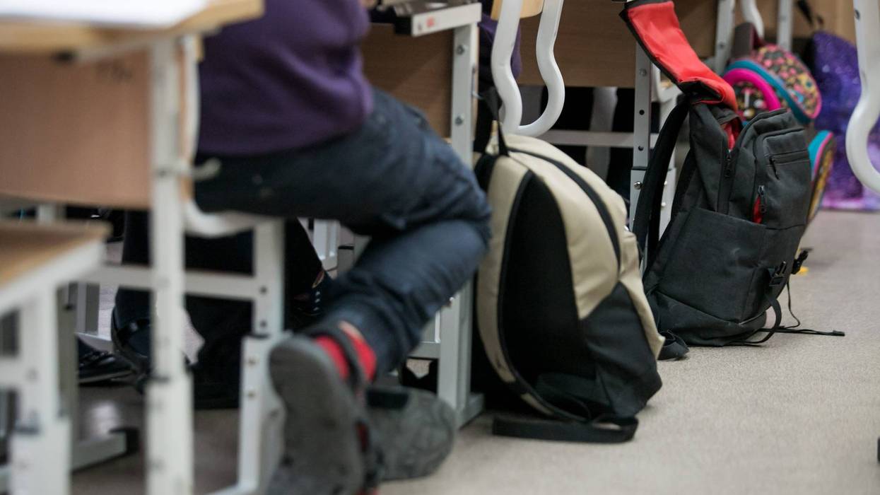 Backpacks next to students at classroom desks