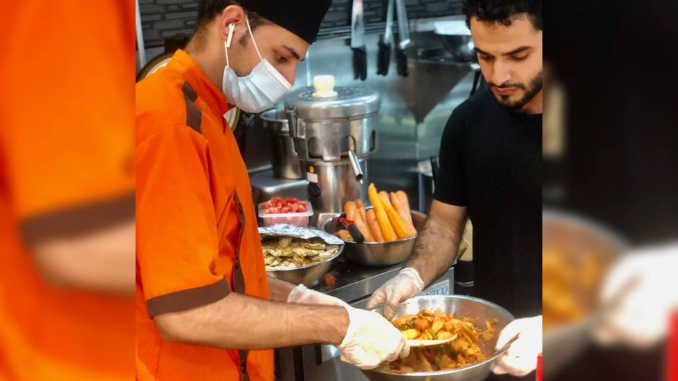 Bakil Nahshal, manager of Healthy Picks Deli, and his assistant manager help prepare food for distribution to Afghan evacuees.
