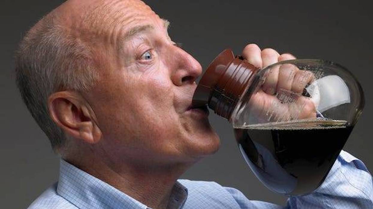 Balding man drinking coffee from pot -