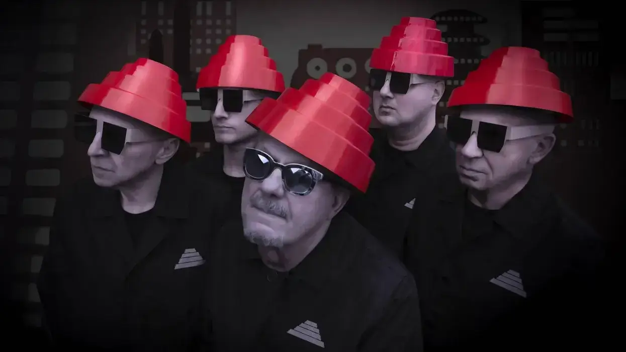 Band Devo members in red energy domes, black sunglasses, and matching black shirts.