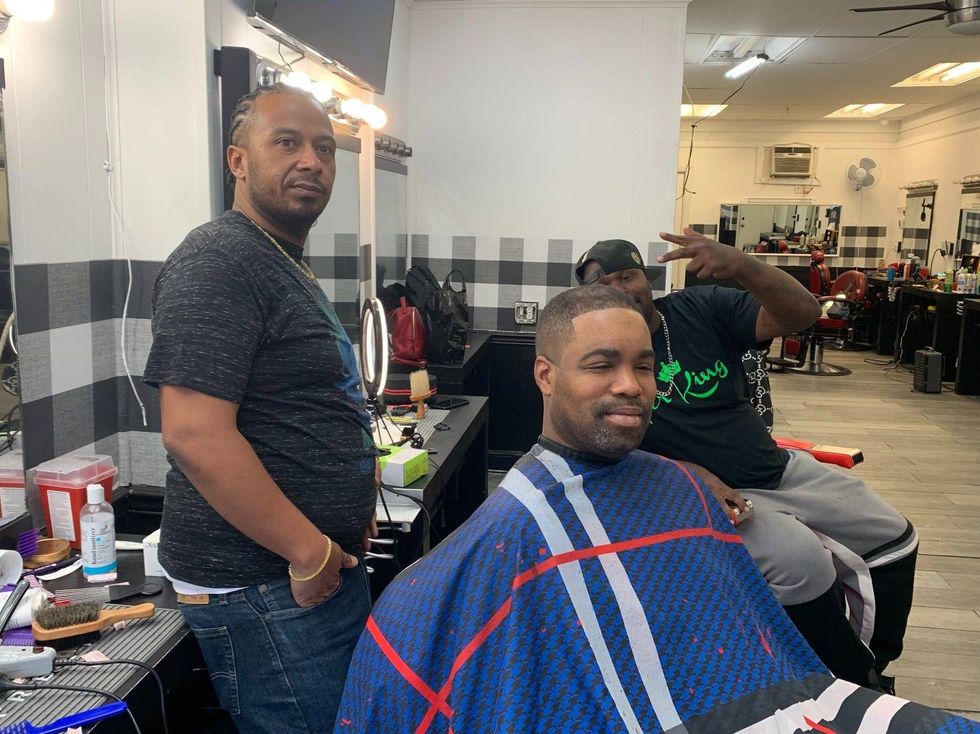 Barber Brandon McDaniel with a client in his chair and another person behind them.