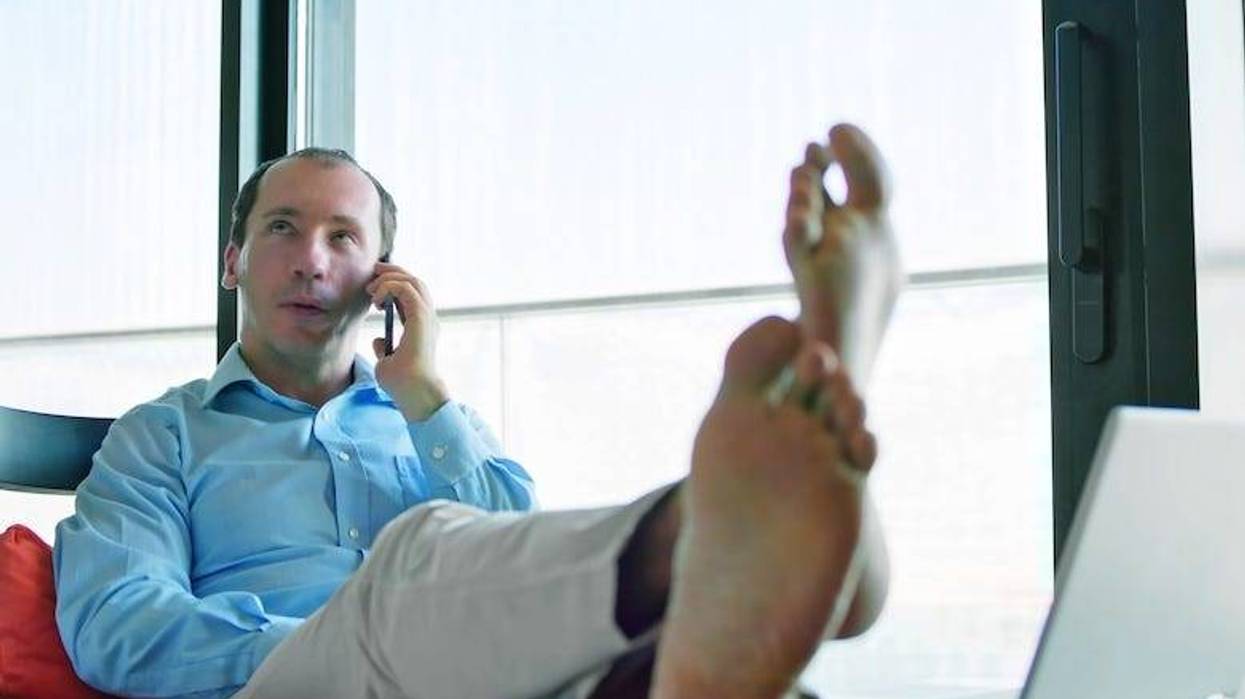 Barefoot man at the office with his feet propped up on a desk