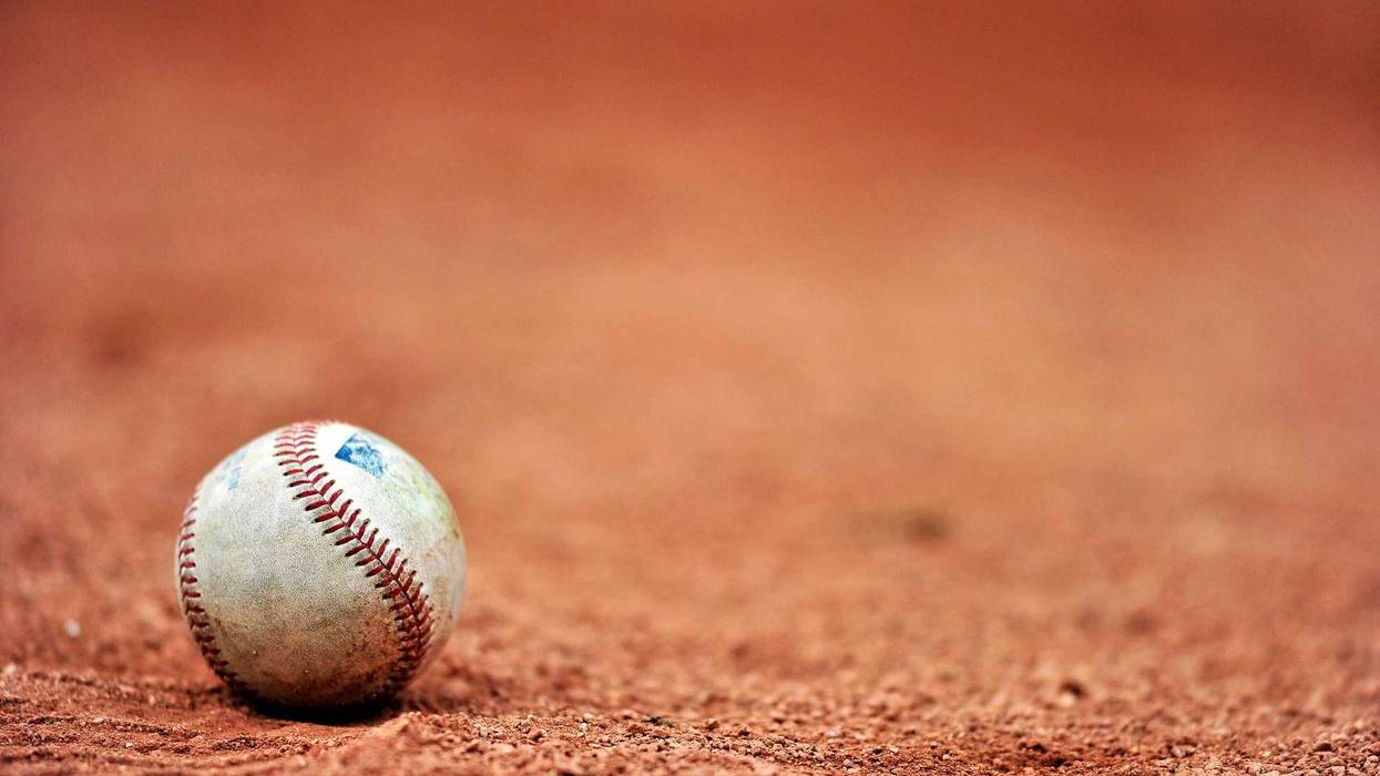 Baseball lying on a dirt field.