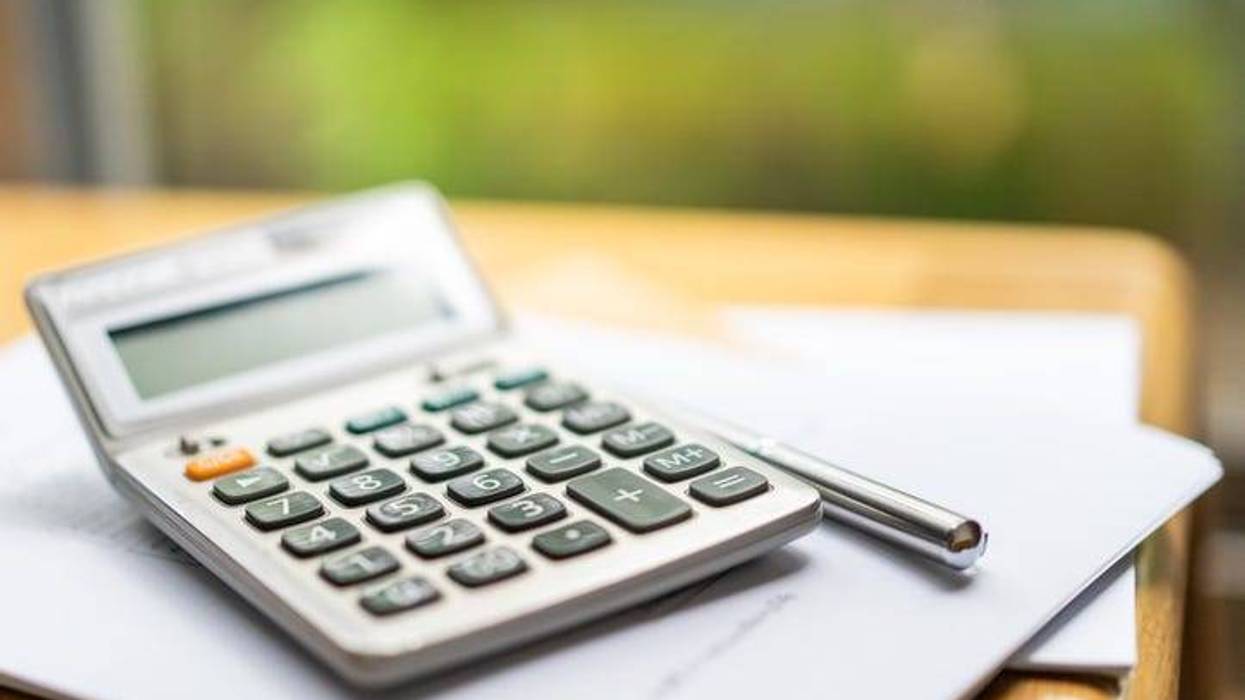 Basic keypad of calculator with a stationaries, laptop computer, business report paper and notepad on the table at home