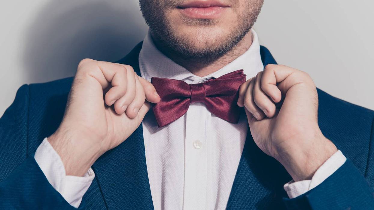 bearded man ties a bowtie at the collar