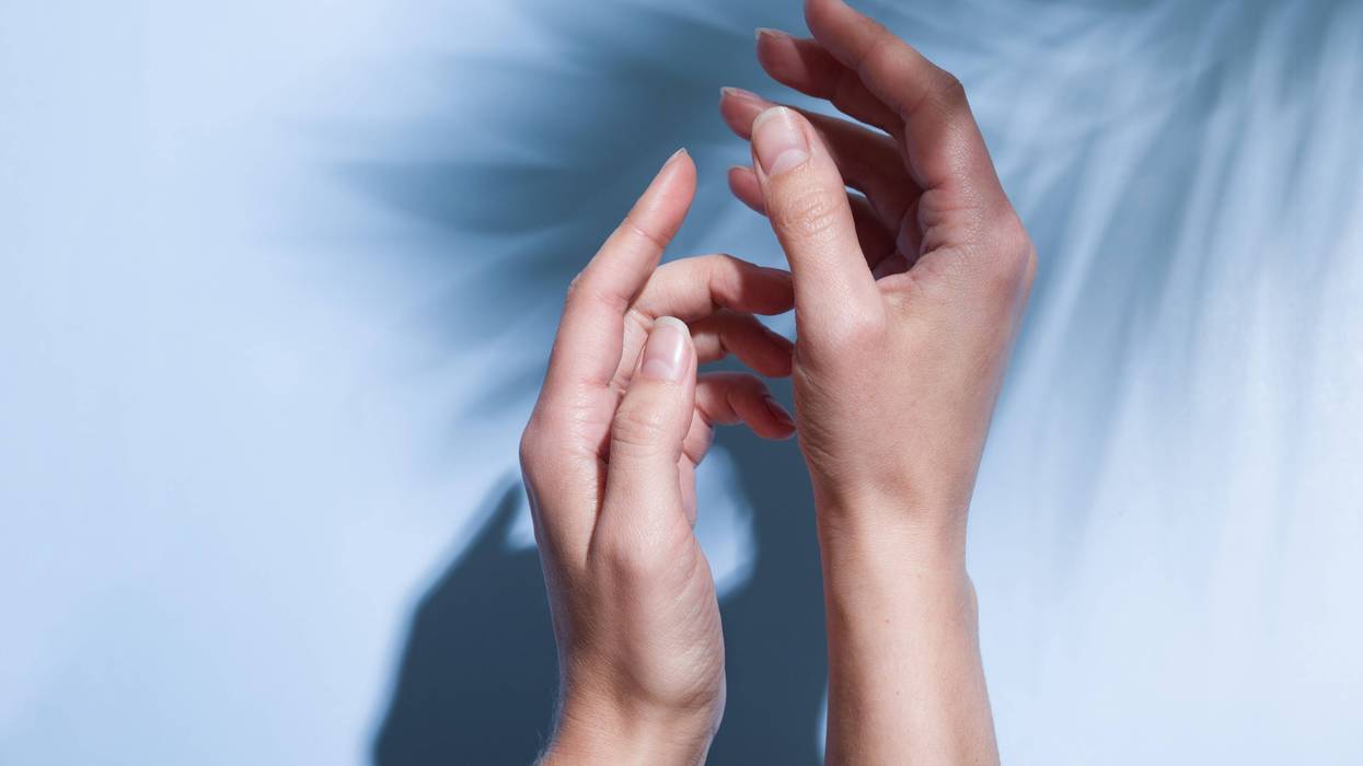 Beautiful female hands in sunlight on a blue background with the shadow of palm leaves