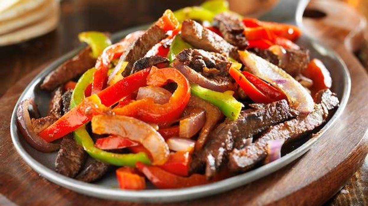Beef fajitas and bell peppers in iron fajita skillet