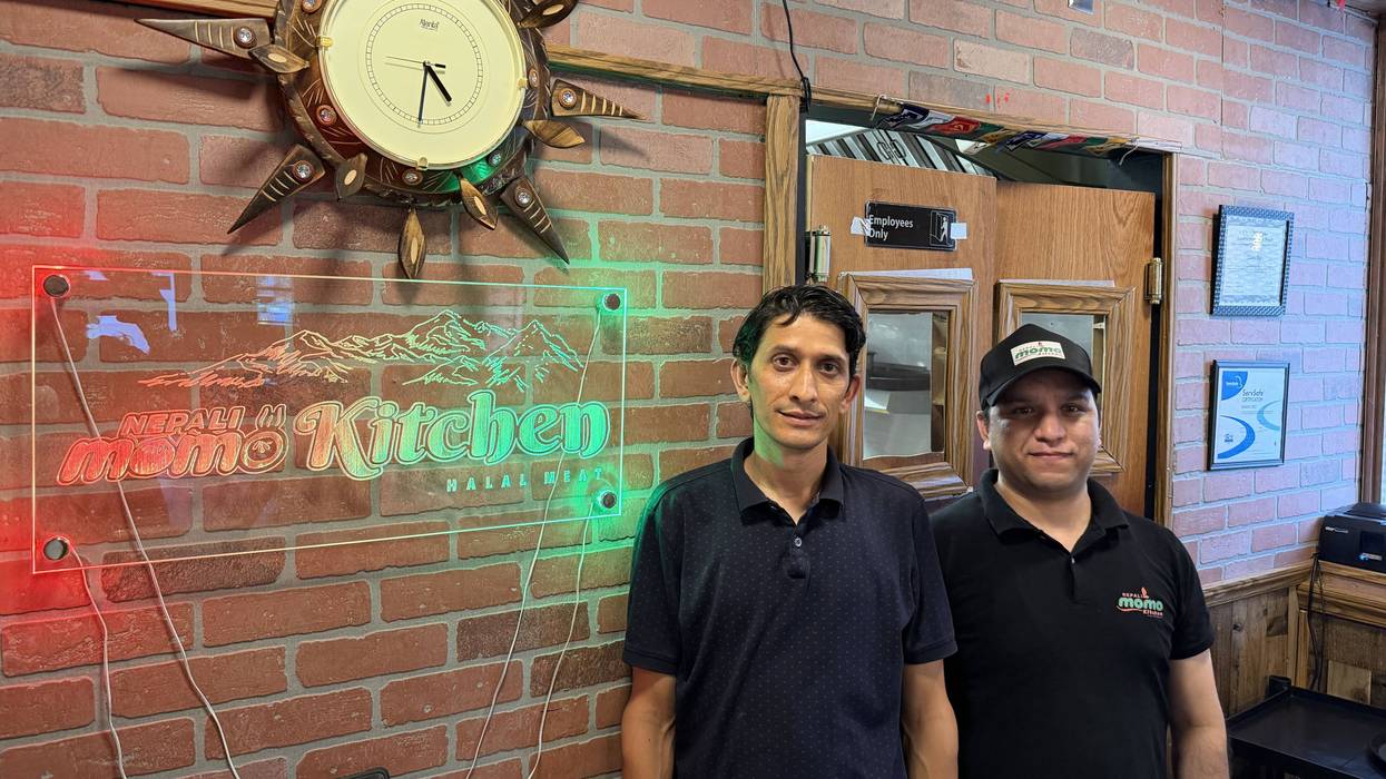 Bhrat Bist and an employee at Nepali Momo Kitchen stand next to a sign for the restaurant.