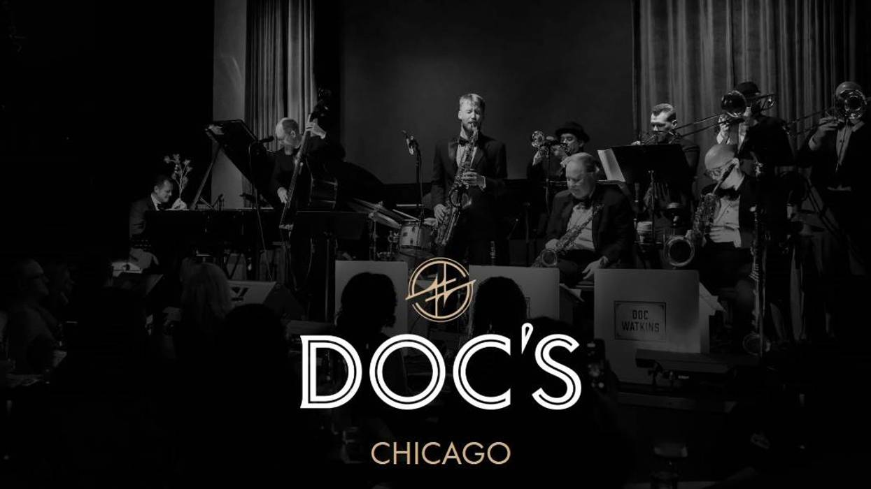 Black-and-white photo of a big band on stage in a dim room