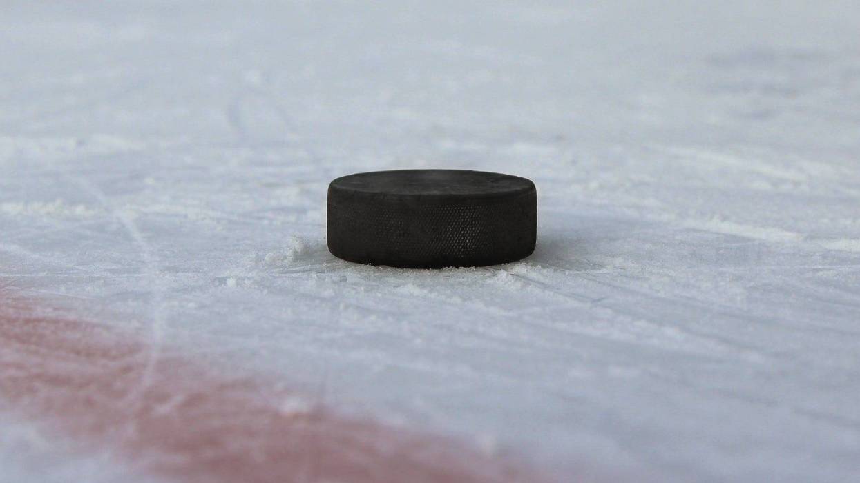 Black hockey puck on the ice - stock photo