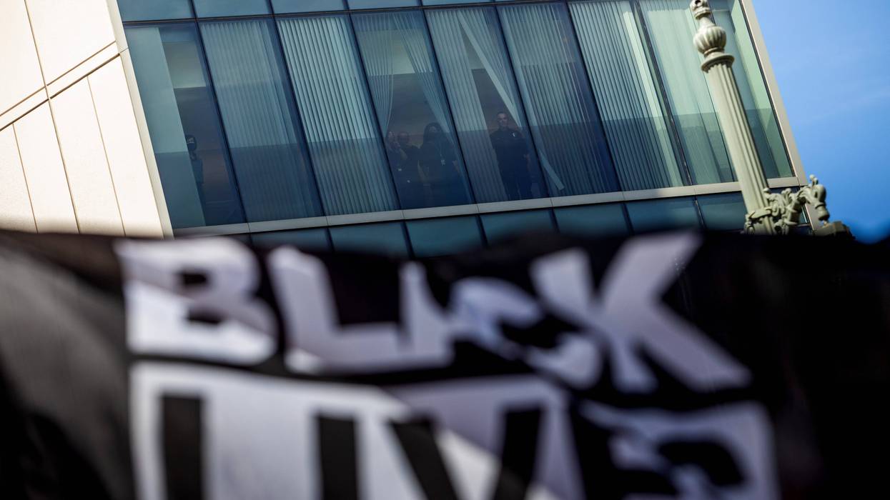 black lives matter flag waves with tall building in the background