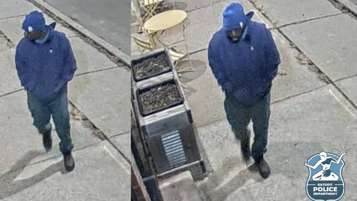 Black man wearing blue jeans, blue hoodie and blue beanie walking on sidewalk