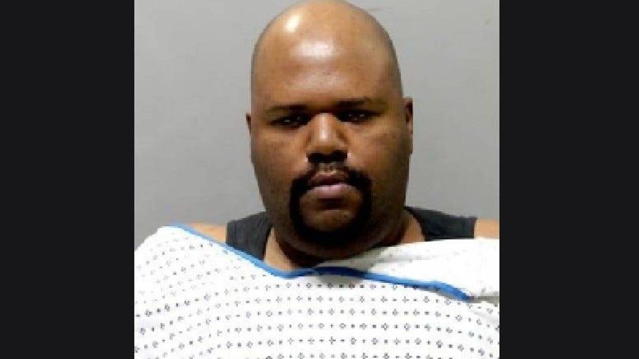 Black man wearing hospital gown with facial hair and bald