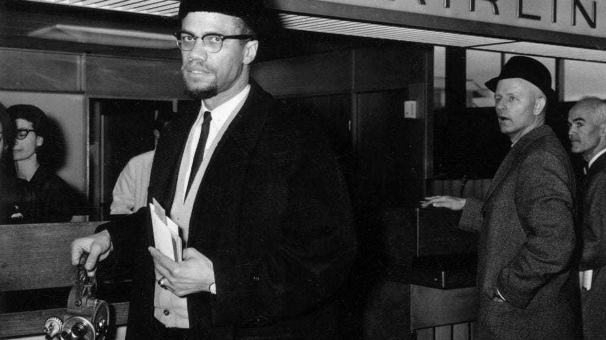 Black Muslim activist Malcolm X (1925 - 1965) arrives at London Airport carrying a portable cinecamera.