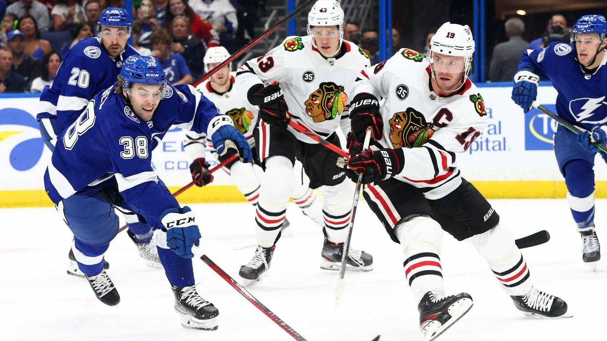 Blackhawks center Jonathan Toews (19) passes the puck as Lightning left wing Brandon Hagel (38) defends.