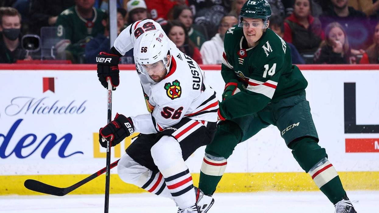 Blackhawks defenseman Erik Gustafsson (56) skates with the puck as Wild center Joel Eriksson Ek (14) defends.