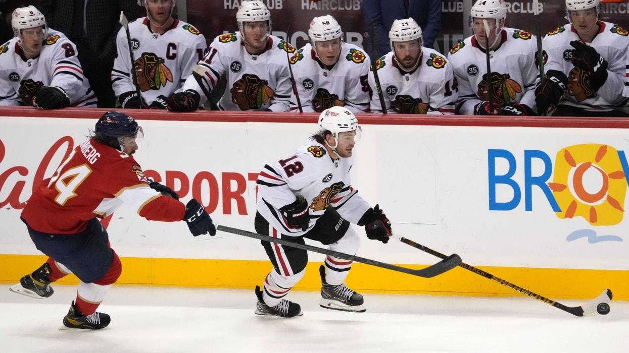 Blackhawks left wing Alex DeBrincat (12) skates with the puck away from Panthers left wing Ryan Lomberg (94).