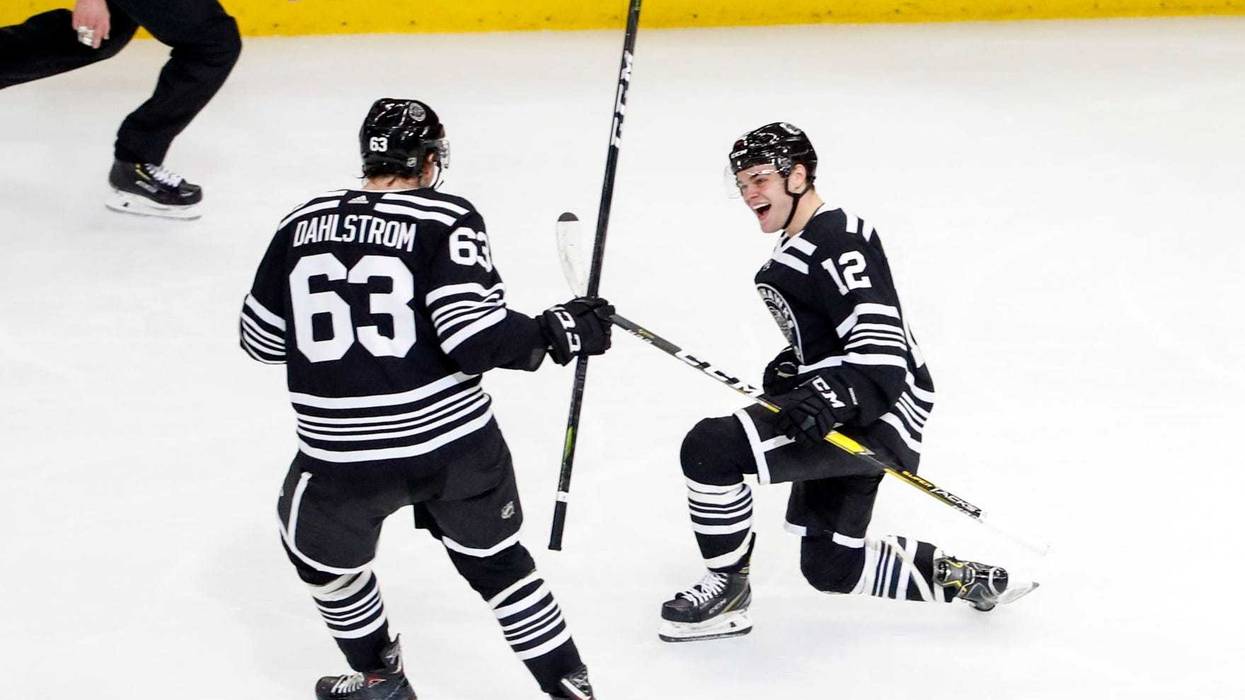 Blackhawks winger Alex DeBrincat (12) celebrates with defenseman Carl Dahlstrom (63) after scoring a goal.