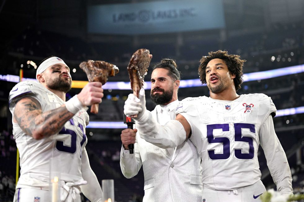 Blake Cashman #51 and Eric Wilson #55 of the Minnesota Vikings celebrate with steak as they are interviewed by Seth Rollins following their 23-10 win against the Detroit Lions at U.S. Bank Stadium on December 25, 2025 in Minneapolis, Minnesota.