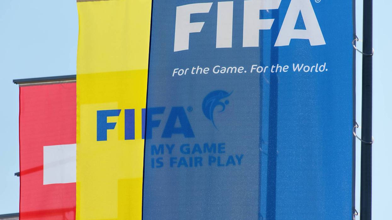 Blue FIFA banner 'For the Game. For the World.' next to yellow FIFA flag and a Swiss flag.