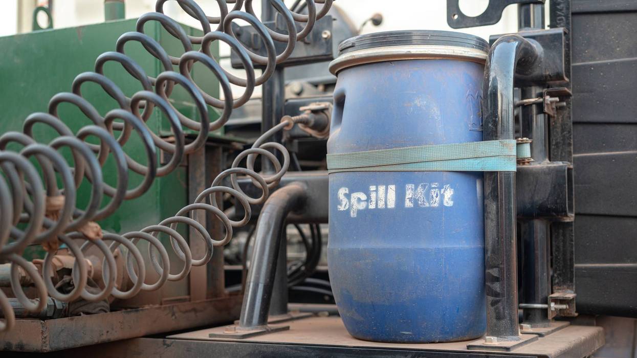 Blue "Spill Kit" barrel strapped to industrial equipment with coiled cables.