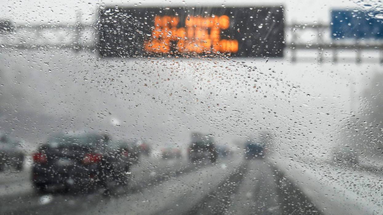 Blurred image of a rainy and snowy car windshield on the highway.