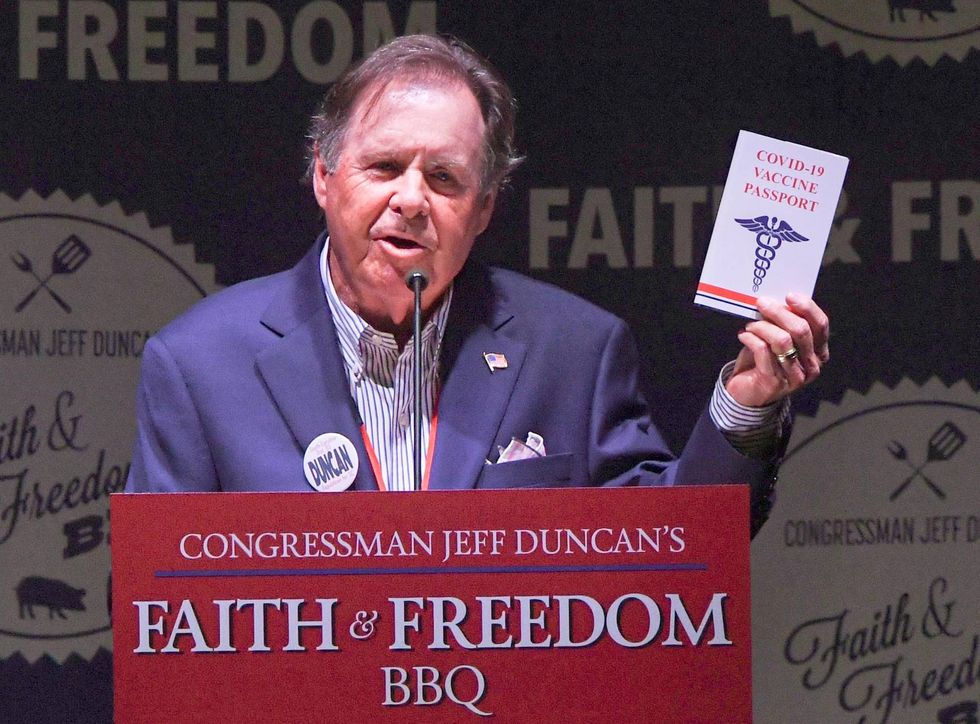 Bob McLain Show host of 106.3 FM holds a booklet with the U.S. Constitution, with the words COVID-19 Vaccine Passport on the cover, during Congressman Jeff Duncan