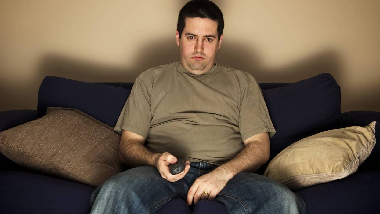 Bored, lazy, overweight man sits on the sofa