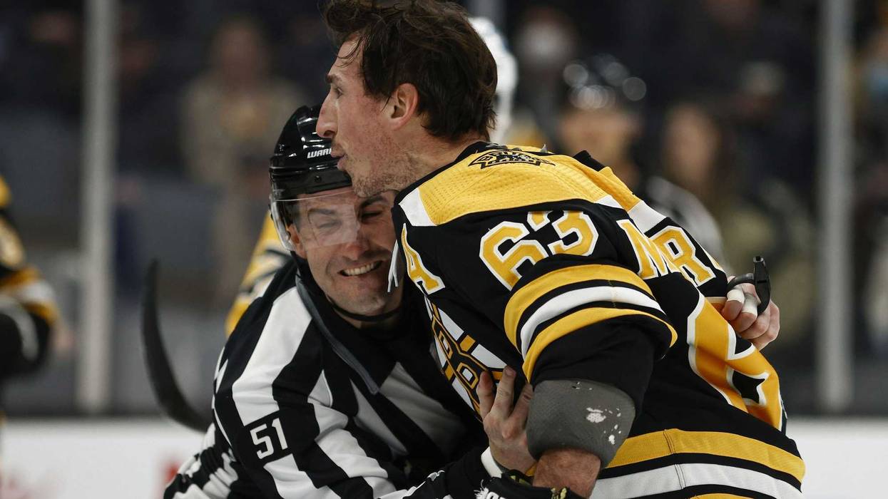 Boston Bruins left wing Brad Marchand (63) is held back by linesman Andrew Smith