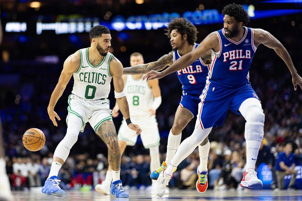 Boston Celtics forward Jayson Tatum (0) passes the ball back to center Kristaps Porzingis (8) in front of Philadelphia 76ers center Joel Embiid (21) and guard Kelly Oubre Jr. (9) during the second quarter at Wells Fargo Center.