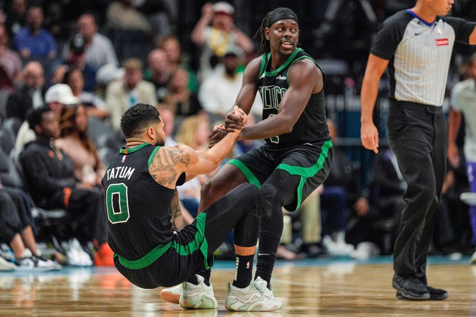 Boston Celtics guard Jrue Holiday (4) helps forward Jayson Tatum (0) onto his feet after a foul late during the second half against the Charlotte Hornets at the Spectrum Center.