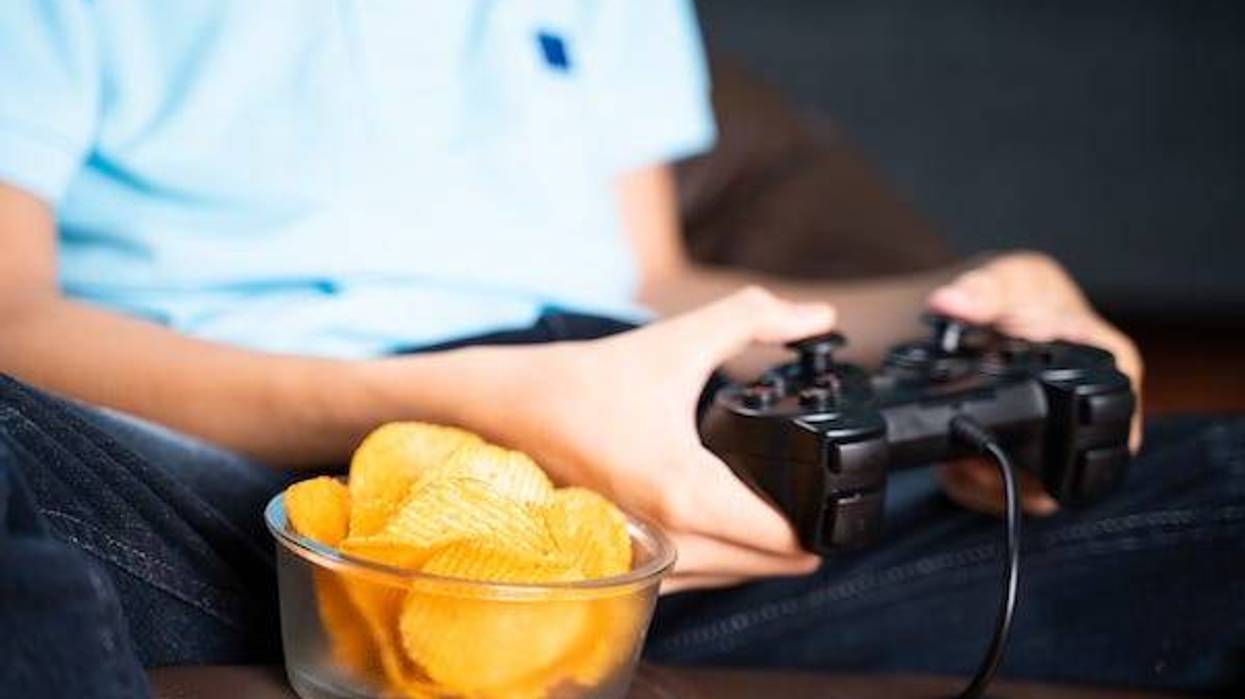 Bowl of chips next a boy playing a video game