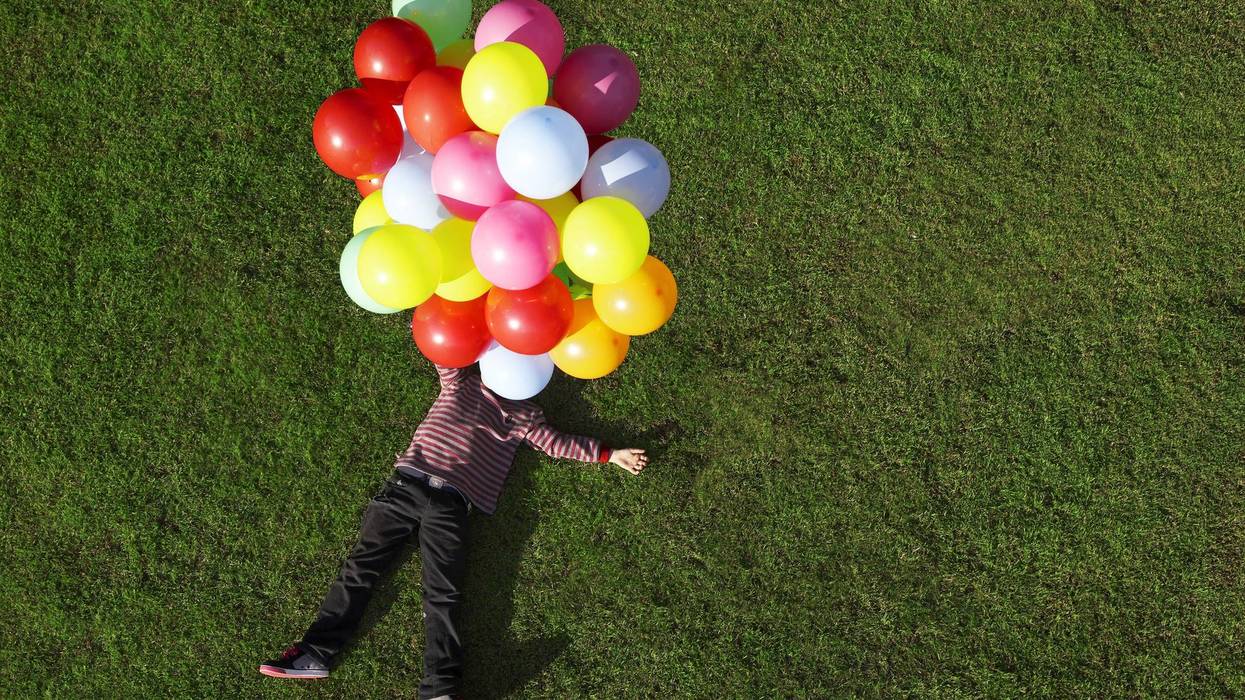 Boy lying on grass with balloons