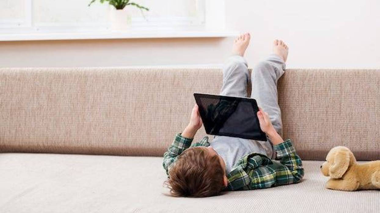Boy playing with digital tablet while sitting on the sofa