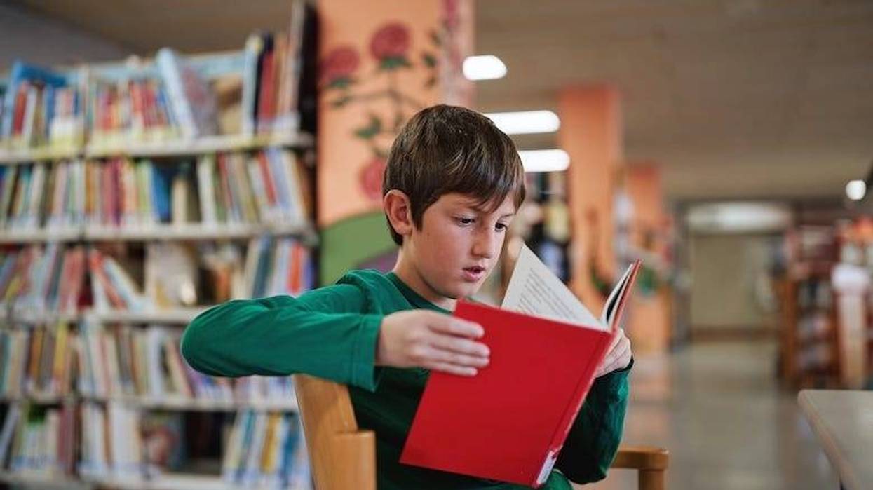Boy reading a red book in a library