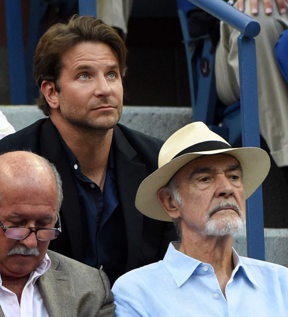 Bradley Cooper (L) and Sean Connery watch Novak Djokovic of Serbia play against Marin Cilic of Croatia during their 2015 US Open Men