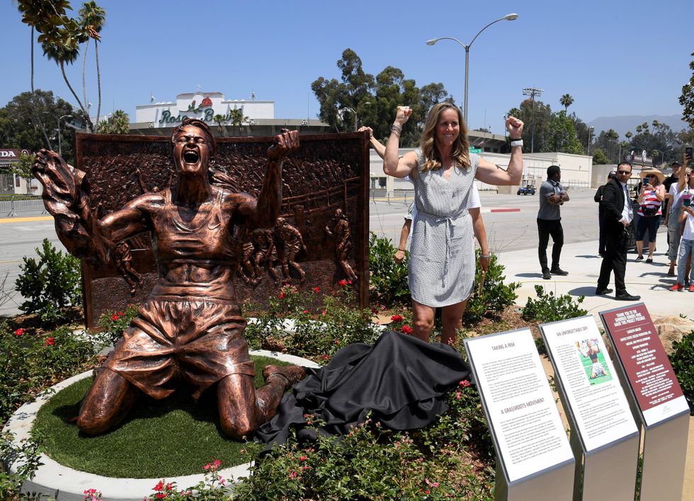 Brandi Chastain poses with statue of herself during an unveiling of a statue honoring the United States win at 1999 Women