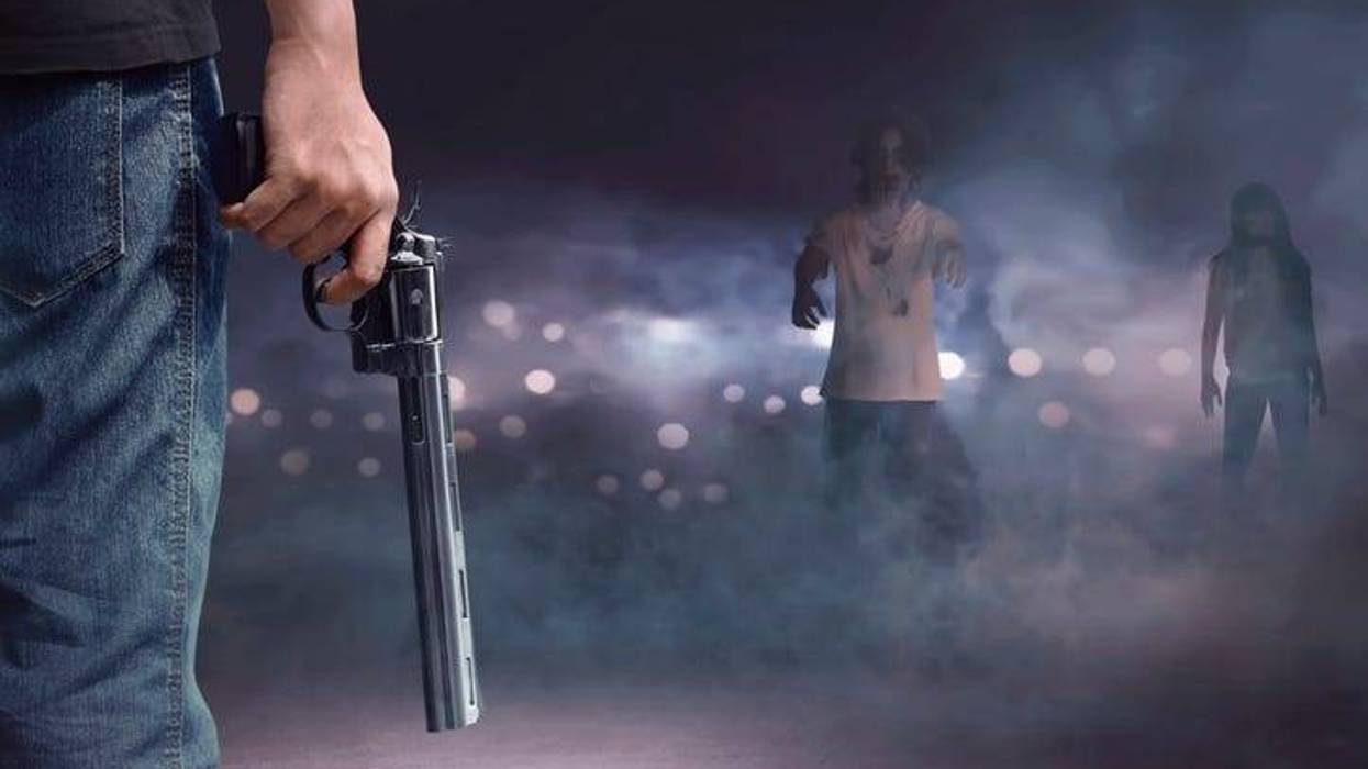 Brave man with jeans pants holding gun looking at zombies walking into him