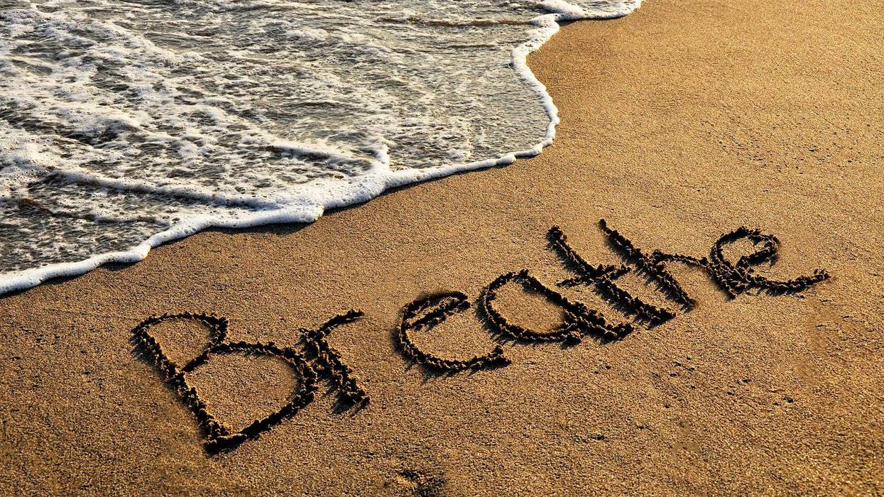 "Breathe" written in sand on a beach