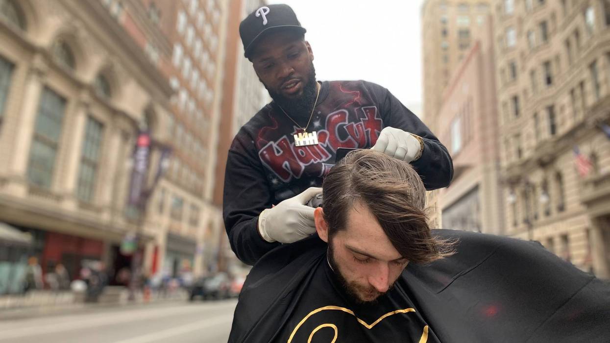 Brennon Jones gives a free haircut in Center City, on the median at Broad and Walnut Streets.