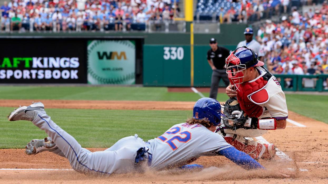 Brett Baty, #22 of the New York Mets, slides safely into home plate ahead of the tag by catcher J.T. Realmuto, #10 of the Philadelphia Phillies, on a two-run single by Michael Perez #35 in the second inning of a game at Citizens Bank Park on Aug. 21, 2022, in Philadelphia, Pennsylvania.