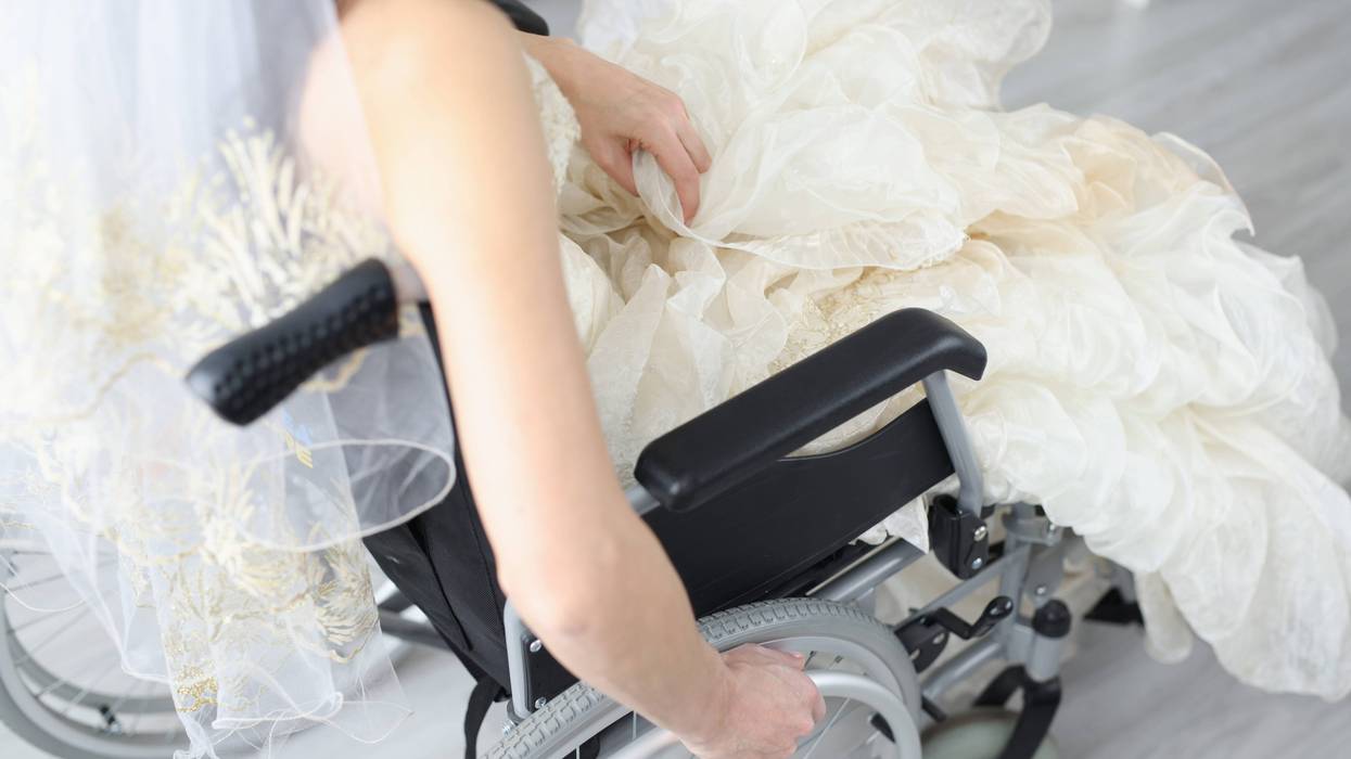 Bride in wedding dress sits in wheelchair